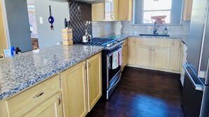 A modern kitchen with wooden cabinets, granite countertops, a stainless steel range, and a built-in oven.