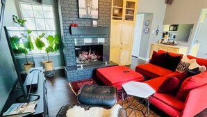 A modern living room with a fireplace, red sofa, and a black leather chair.