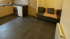Une cuisine moderne avec des meubles en bois, un four encastré et un coin repas comprenant un canapé gris et une petite table.