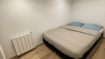Une chambre à coucher avec un lit, un radiateur et un plancher en bois.
