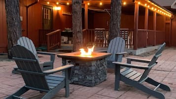 A wooden cabin with a stone fire pit and Adirondack chairs.