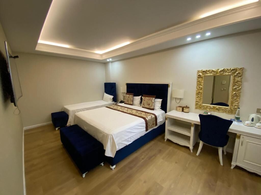 Een slaapkamer met een tweepersoonsbed, nachtkastjes, een bureau, een stoel en een grote spiegel.