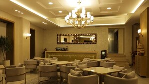 A hotel lobby with a chandelier, a reception desk, and multiple seating areas. - Vila Brais (Durrës)