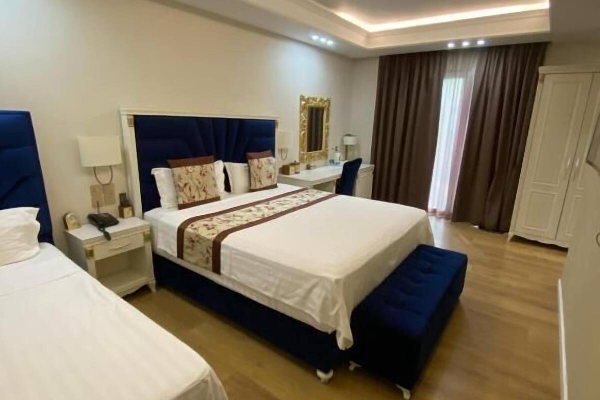 Ein Hotelzimmer mit zwei Betten, einem Schreibtisch, einem Stuhl, einem Kleiderschrank und einem Badezimmer.