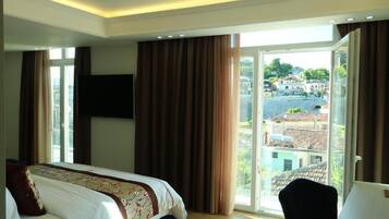 Suite, vistas a la ciudad | Tabla de planchar con plancha y ropa de cama
