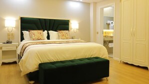 A neatly arranged bedroom with a large bed, bedside lamps, a green upholstered bench, and a wardrobe. - Vila Brais (Durrës)