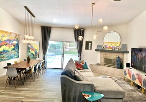 Relax in the spacious living room with a comfortable sofa, dining table, and large flat-screen TV.