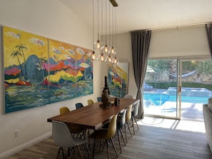 A dining area with a wooden table, colorful chairs, and a large painting on the wall. - Resort Paradise with spa and pool (Cathedral City)