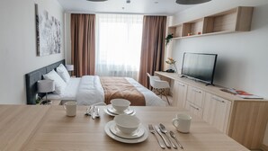 A modern hotel room with a neatly made bed, a dining table set with plates and cutlery, a television, and a desk with a chair. - YE'S APART ASTANA (Astana)