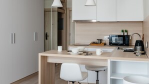 A modern kitchen with white cabinets, a wooden countertop, a microwave, a coffee maker, and two pendant lights. - YE'S APART ASTANA (Astana)