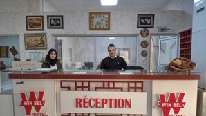 A reception desk at Win Bel Hotel with a clock and framed pictures on the wall. - Winbel Hotel (Hassi Messaoud)