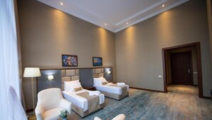 A hotel room with two beds, a chair, a small table, and artwork on the walls.
