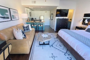 A hotel room with a bed, a sofa, a coffee table, and a view of the kitchen and living area. - Studio 580 Main (Park City)