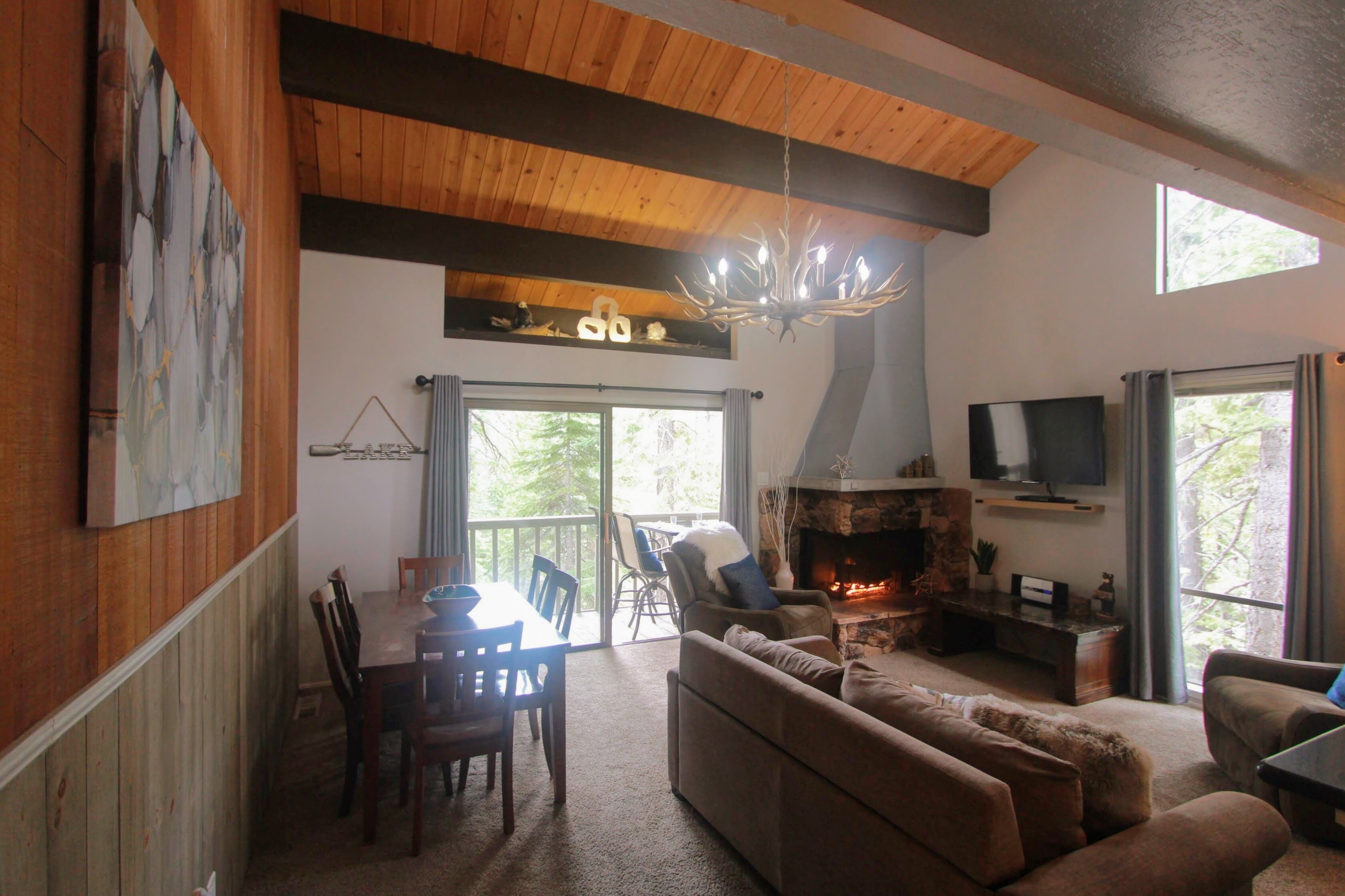 A cozy living room with a fireplace, wooden ceiling, and a dining area with a table and chairs.