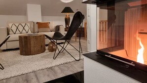 Ein modernes Wohnzimmer mit Kamin, einer Couch, einem Couchtisch und einem Sessel.