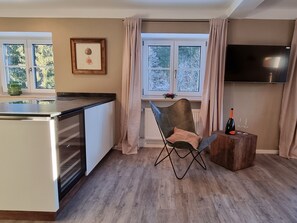 Una cocina moderna con comedor, una silla de madera y una botella de vino sobre una mesita.
