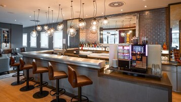 Uma área de bar com bancos, balcão e máquina de café.