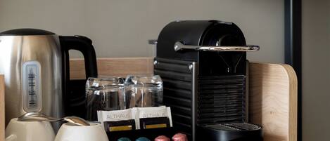 A coffee station with a kettle, coffee machine, and labeled containers of coffee.