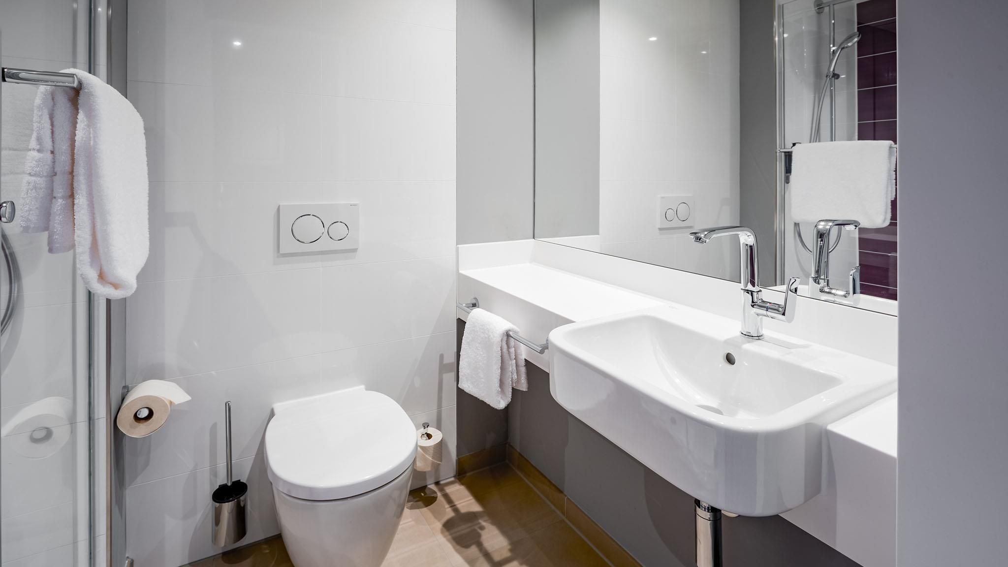 A modern bathroom with a toilet, sink, and shower.