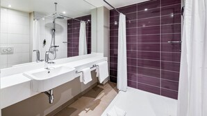Un baño moderno con dos lavamanos, ducha y un espejo grande.