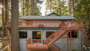 Eine zweistöckige Holzhütte mit einer Holzterrasse und einer Treppe.