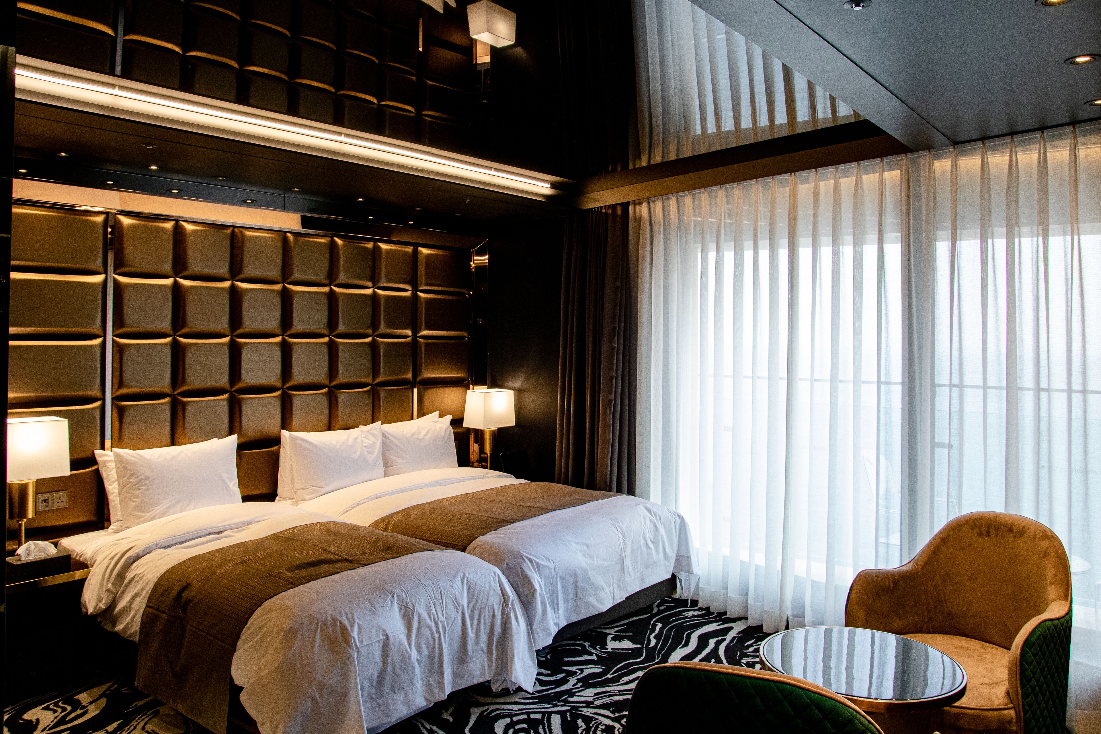 A hotel room with a large bed, two bedside tables, a chair, and a small table.