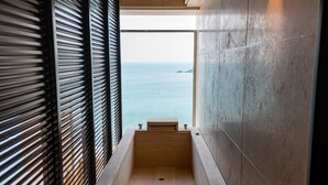 A modern bathroom with a wooden bench, a round wooden bowl, and a view of the sea. - Best Louis Hamilton Hotel Ocean Terrace (Busan)