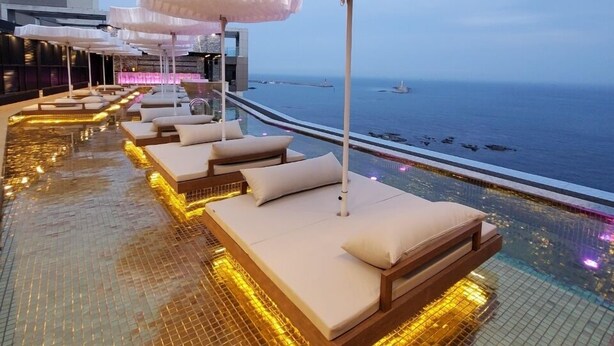A rooftop infinity pool with lounge chairs and umbrellas, overlooking the sea. - Best Louis Hamilton Hotel Ocean Terrace (Busan)