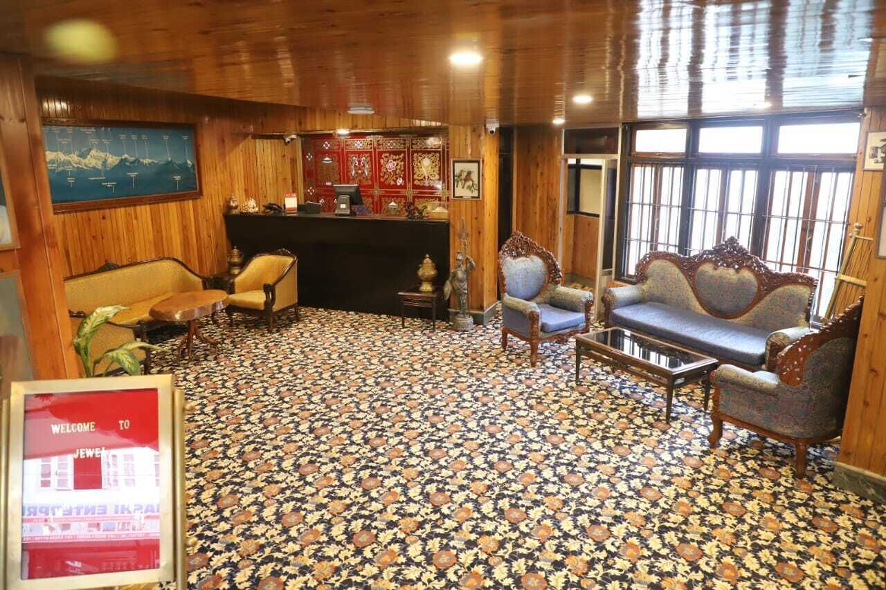 Une pièce dotée d’un tapis à motifs, de murs en bois, d’un canapé, de fauteuils, d’une petite table et d’un coin bar décoré de rouge et d’or.