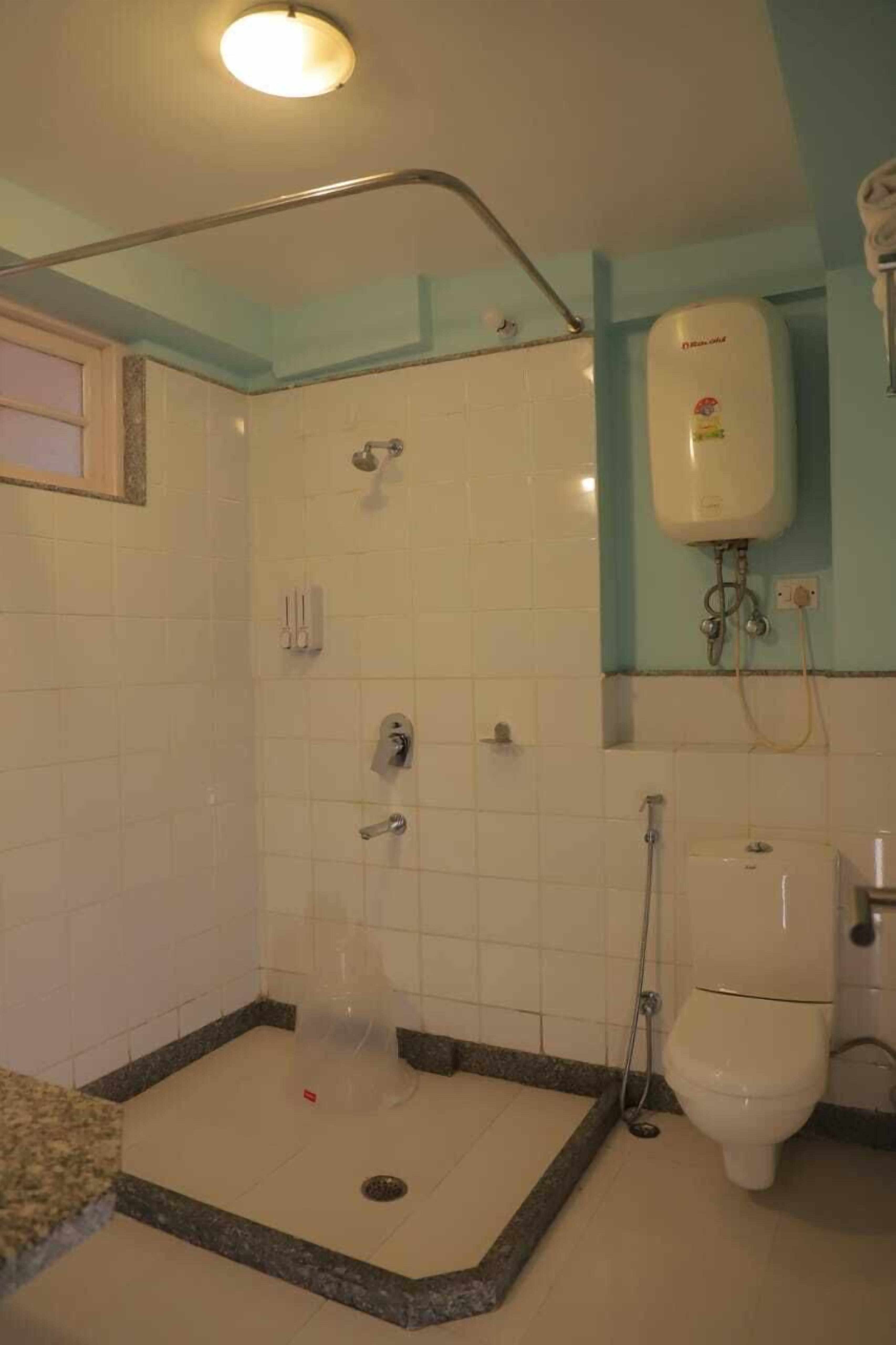 A bathroom with a shower, toilet, and a water heater.
