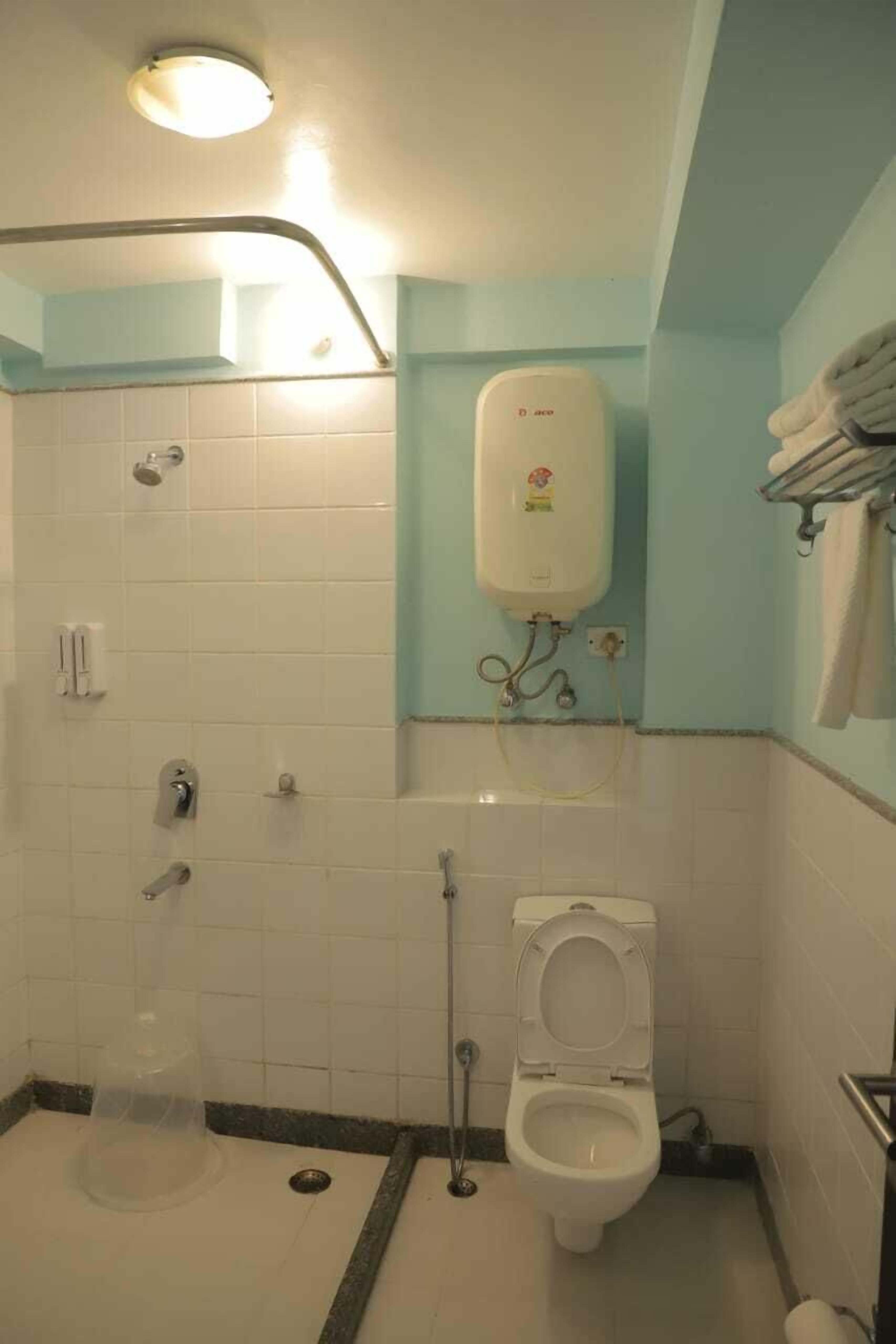 A bathroom with a shower, toilet, and hand dryer.