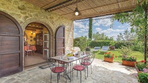 A stone patio with a table and chairs, a wooden door, and a view of a garden.