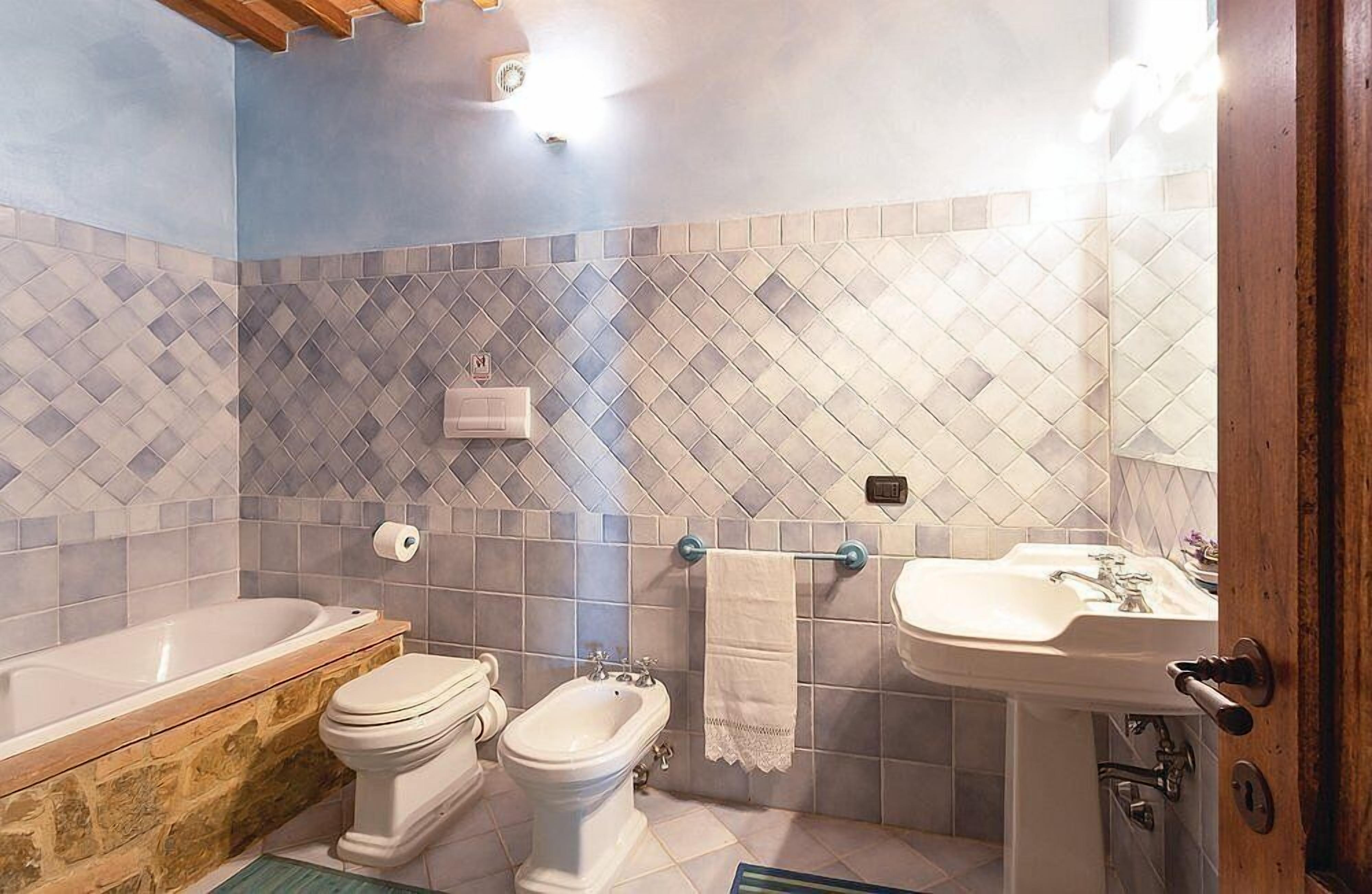 Et badeværelse med badekar, toilet, pissoir og håndvask.