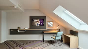 Une pièce moderne et compacte avec un plafond en pente, un bureau intégré, une chaise, une petite table et une grande fenêtre.