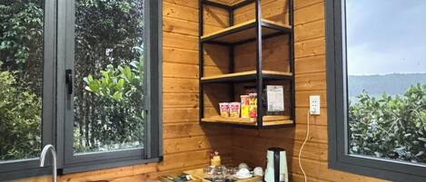 Una cocina con paredes de madera, encimera de granito, un lavamanos, una cafetera y estantes con utensilios de cocina.