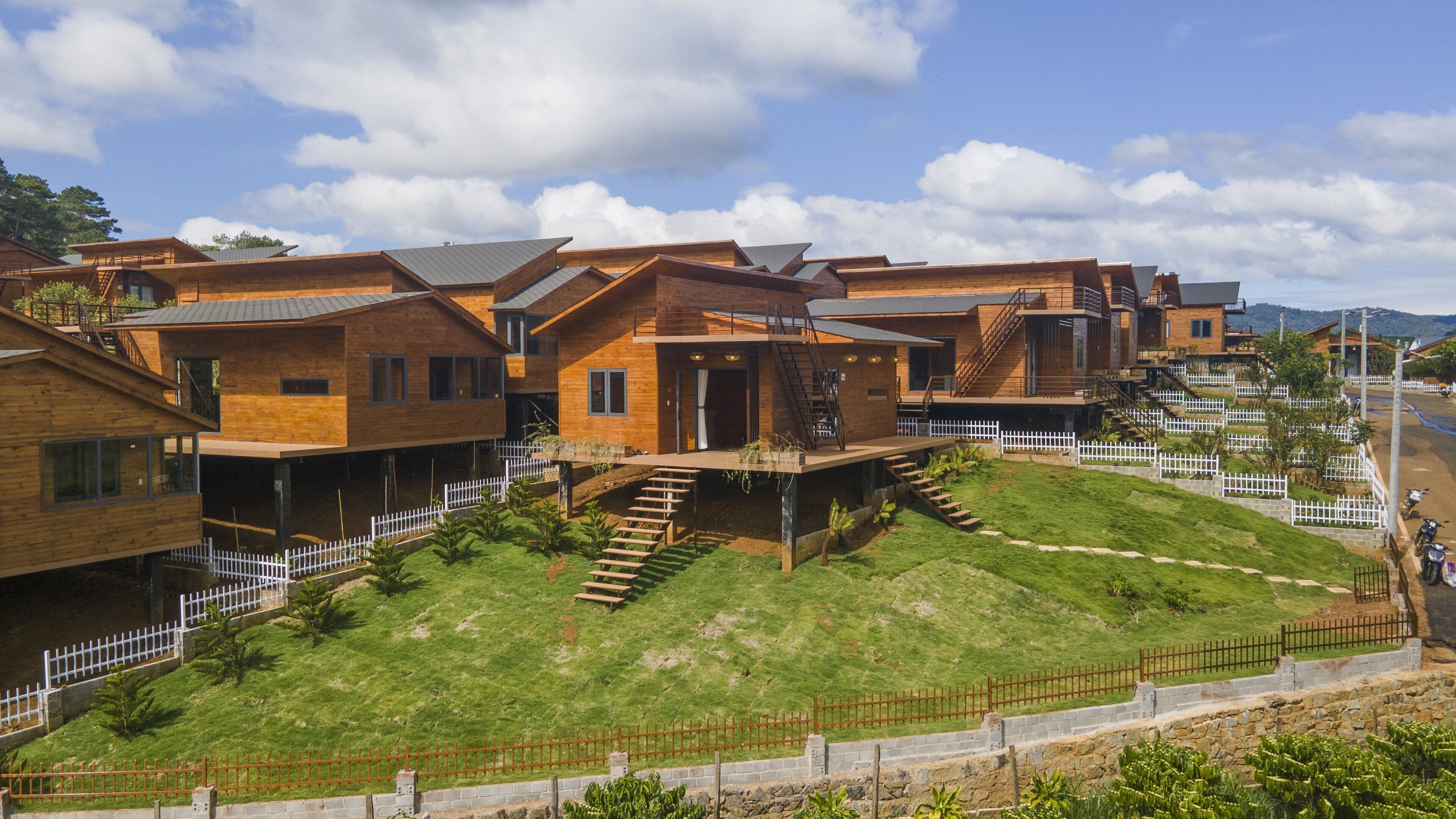 Un moderno complejo residencial con varias casas de madera, cada una con un balcón y una escalera que conduce a una terraza plana.