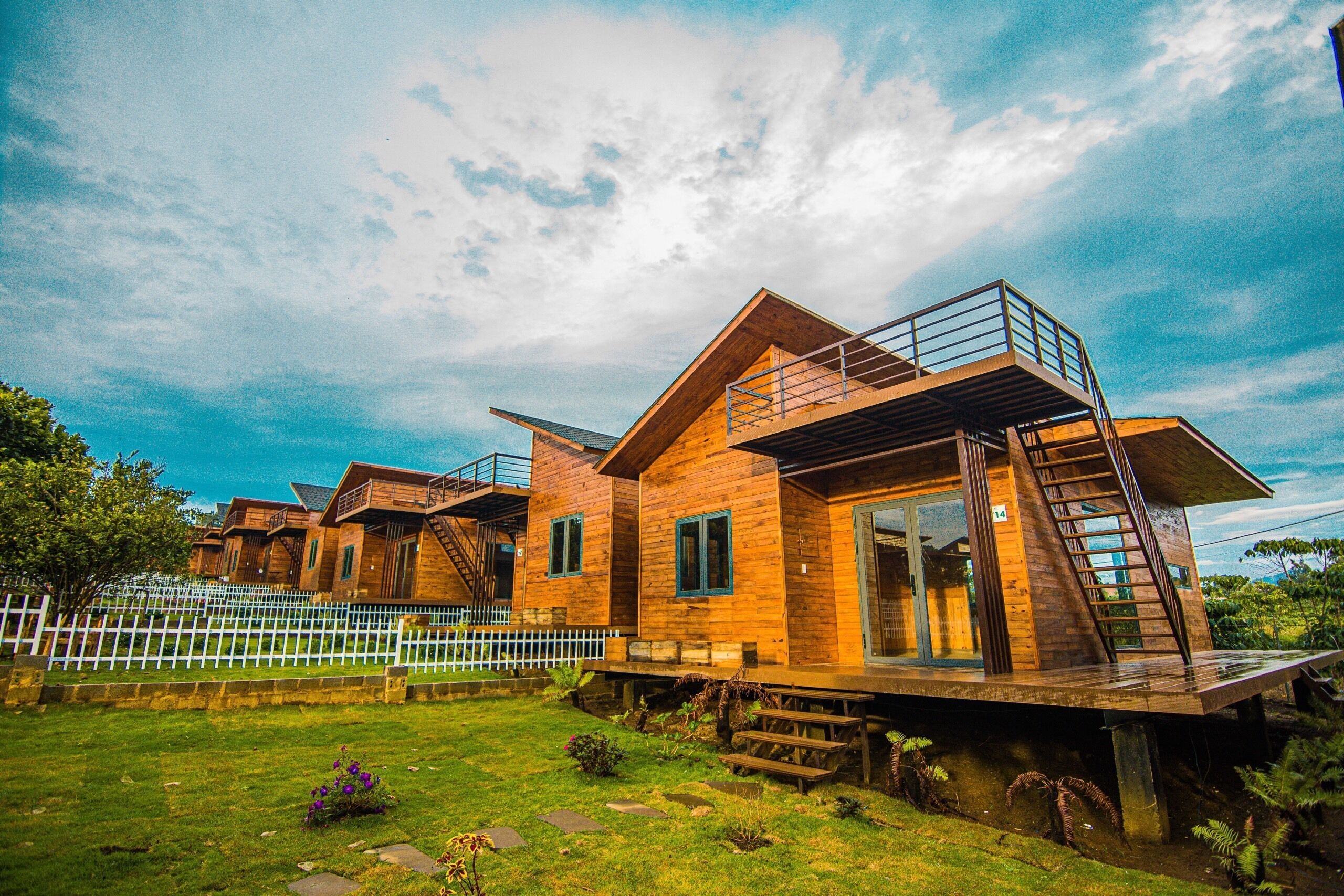 A wooden cabin with a balcony and a staircase leading to a deck.