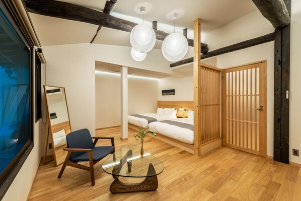 A modern room with a glass coffee table, a sofa, a chair, and a wooden wardrobe.