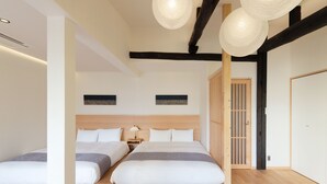 Una camera da letto moderna con due letti, travi in legno, un'ampia finestra e una tradizionale porta scorrevole giapponese.