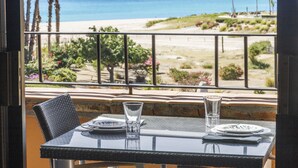 A table with two plates and two glasses, set against a backdrop of a beach and palm trees.