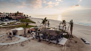 A beachfront property with a pool, outdoor seating, and a view of the ocean.