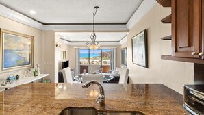 A kitchen with granite countertops, stainless steel fixtures, and a view to the outside.