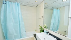 A modern bathroom with a white bathtub, a sink, and a mirror. - BRZ - Budget studio with balcony (Dubai)