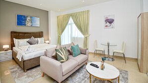 A modern bedroom with a bed, a sofa, a round coffee table, and two chairs. - BRZ - Budget studio with balcony (Dubai)