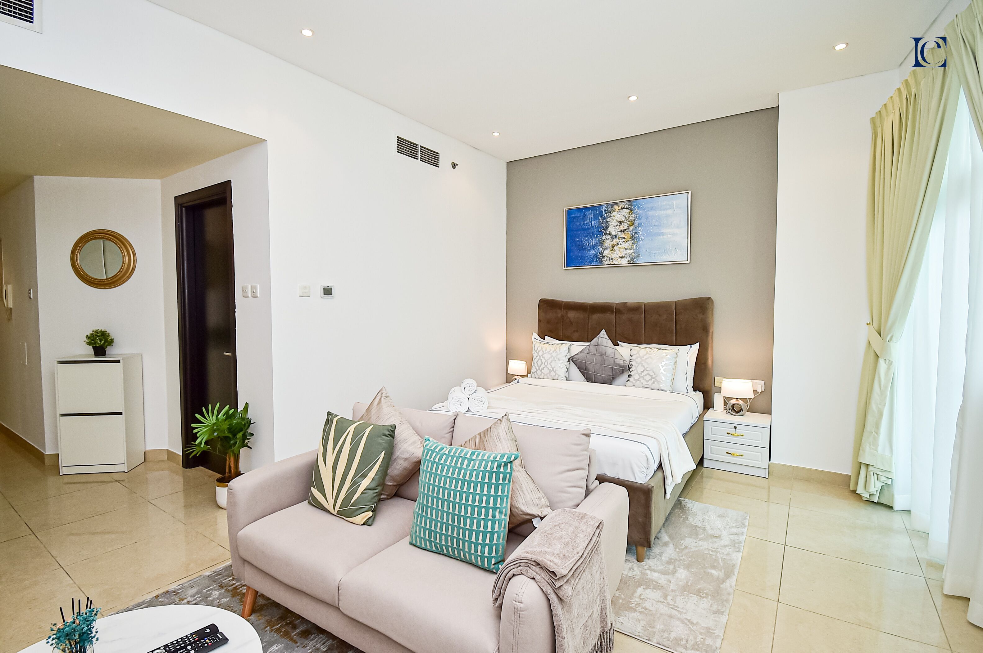 Een moderne slaapkamer met een groot bed, een bank, een nachtkastje en een bijzettafeltje.