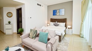 A modern bedroom with a large bed, a sofa, a bedside table, and a nightstand. - BRZ - Budget studio with balcony (Dubai)