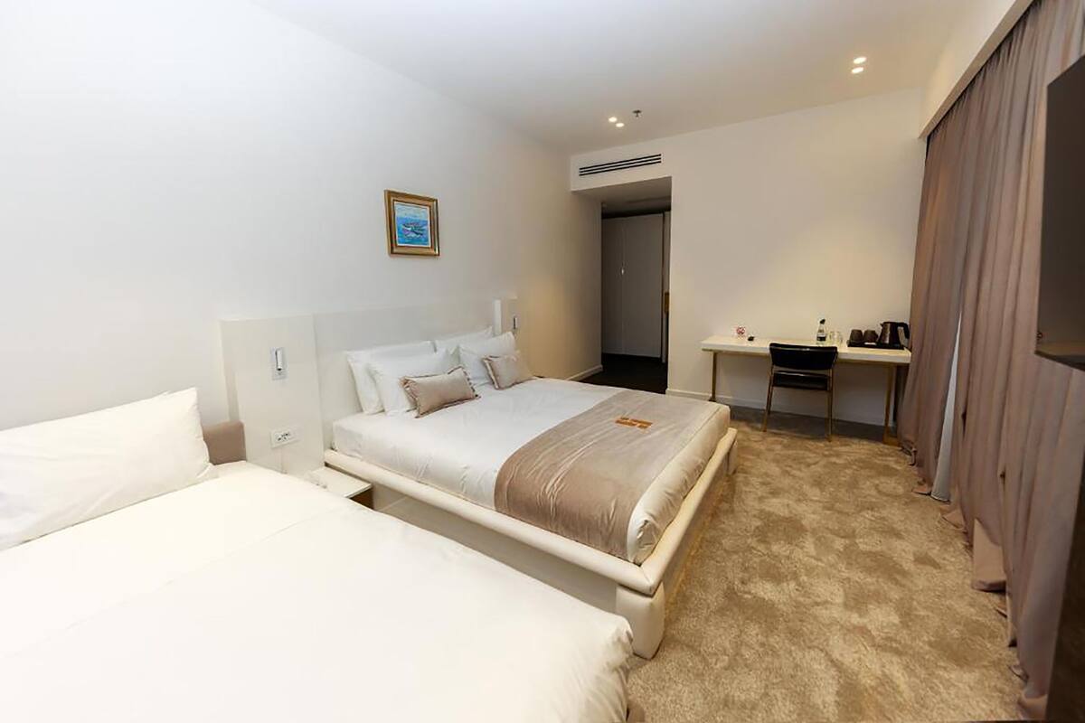 A hotel room with a large bed, a desk with a chair, and a wardrobe.