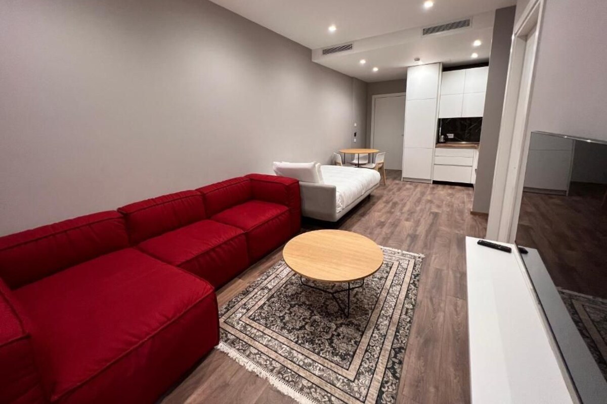 A modern living room with a red sofa, a round coffee table, and a patterned rug.