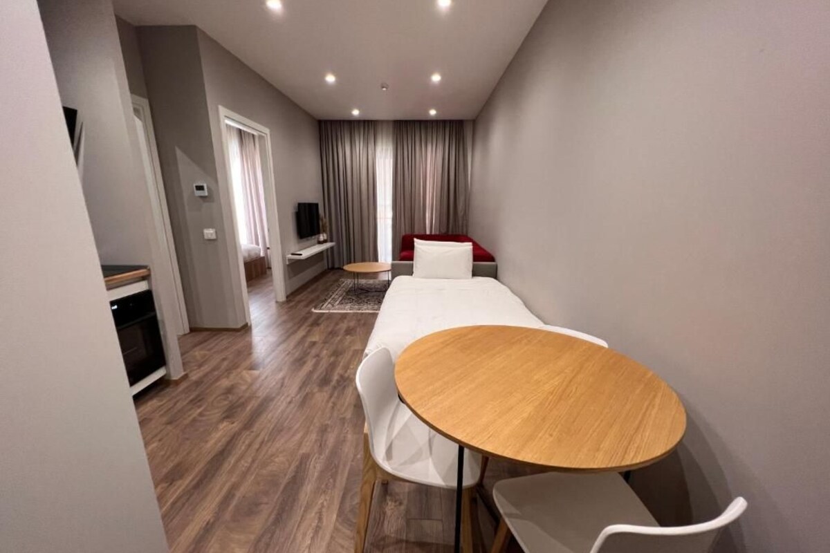 Een moderne woonkamer met een houten eettafel, witte stoelen, een rode bank en een televisie.