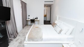 A modern hotel room with a large bed, a desk, and a flat-screen TV. - Habitat Hotel Tirana (Tirana)